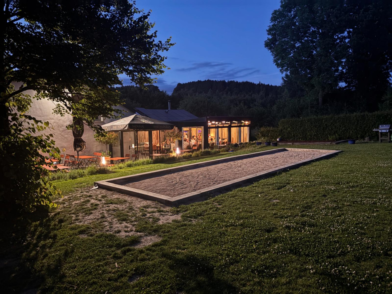 Le restaurant vu du jardin avec une piste de pétanque en avant-plan