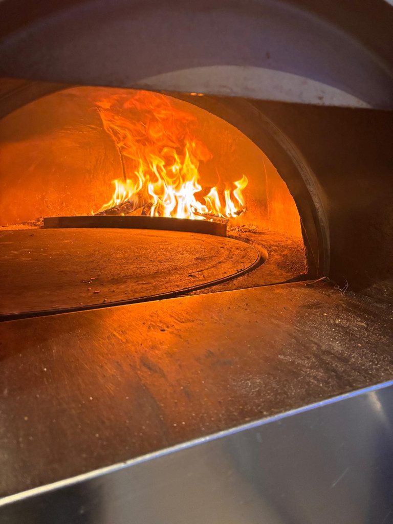 L'intérieur de four laissant apparaître des bûches en bois enflammées